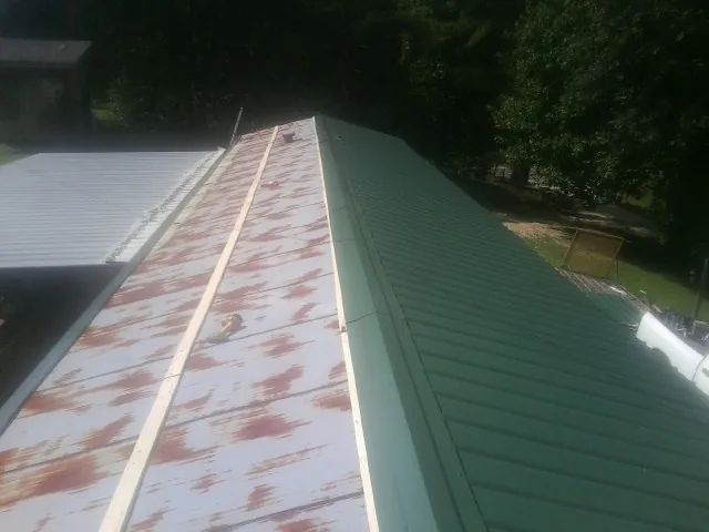 Old rusted panels beside newly installed green metal roofing — Wind Damage Roof Repair by Roofing Brothers in Mounds