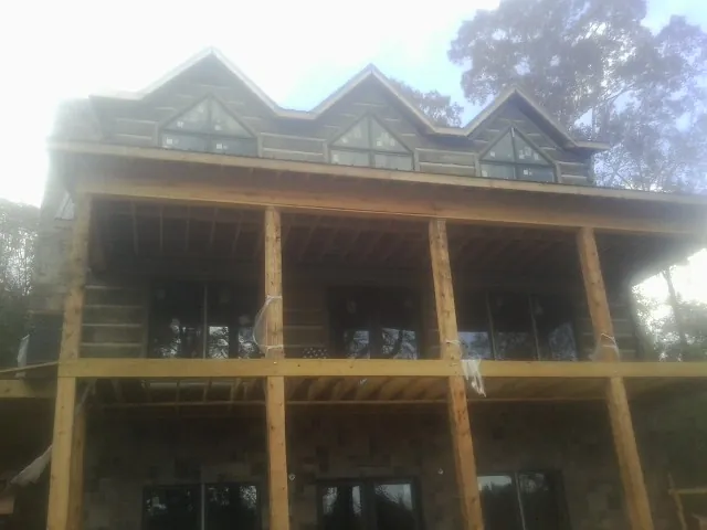 Dormers and porch framing on a large log home under construction — Roof Coating work by our crew in Mounds