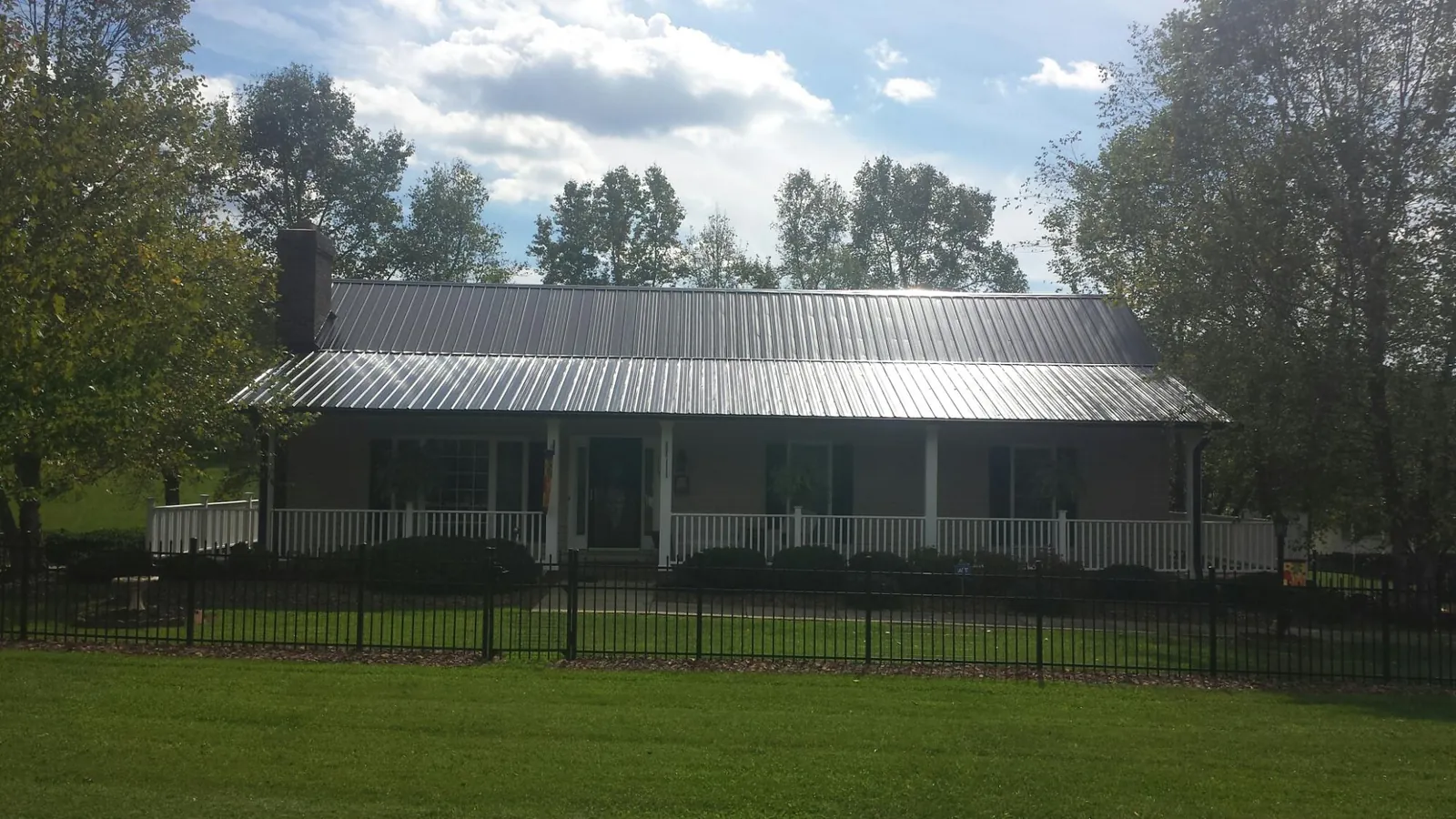 Gray metal roof on a brick ranch with a full width front porch — Gutter Guard Installation work by our crew in Mounds