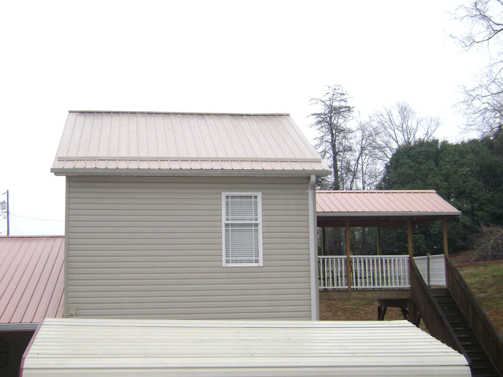 Tan metal roofs on a two story addition and attached porch, from a Roof Replacement job in Mounds
