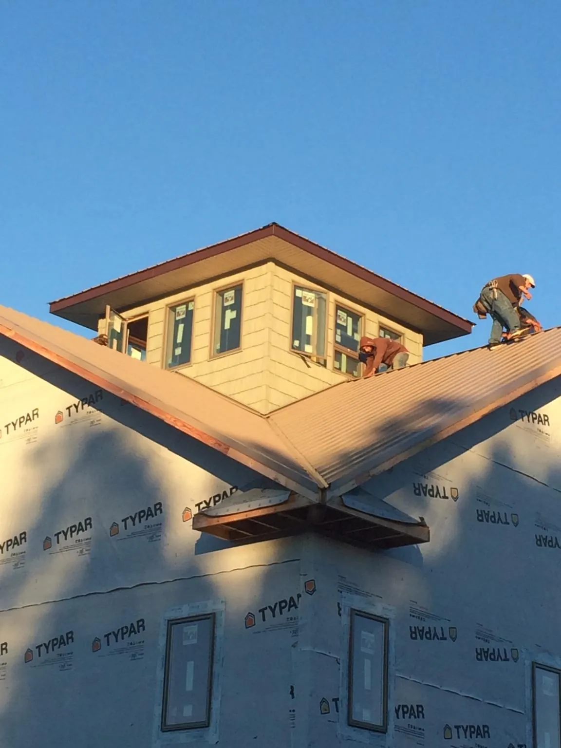 Roofers working around a rooftop cupola on a new metal roof at sunset — Roof Waterproofing in Mounds by Roofing Brothers